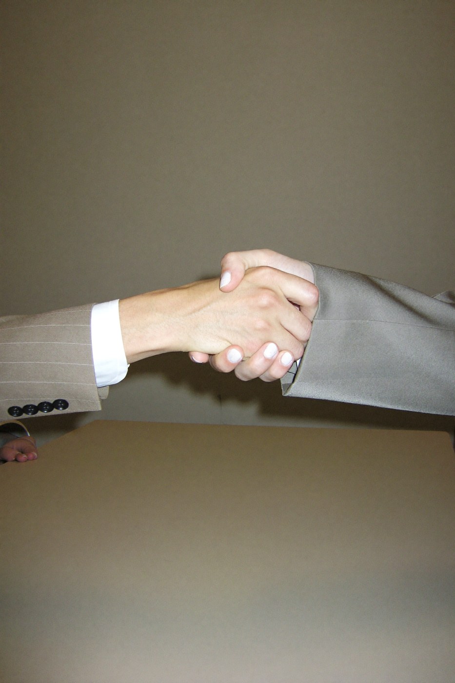 Extreme close-up of a stiff corporate handshake, white-knuckle grip